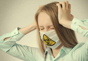 young blonde girl holds her head in medical mask with virus sign