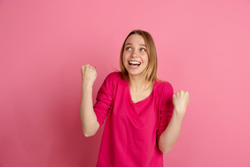 Celebrating winner. Caucasian young woman's portrait isolated on pink studio background, monochrome. Beautiful female model. Concept of human emotions, facial expression, sales, ad, trendy.