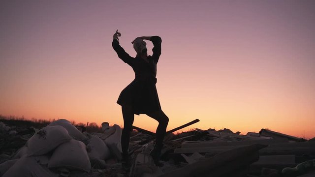 girl in a black dress, in tights and a gas mask dancing at sunset on the ruins