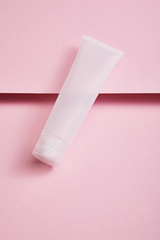 High angle view of empty plastic cosmetic cream tube on pink background