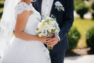 Beautiful and sophisticated wedding bouquet close-up holds the bride in her hands next to the groom. Wedding bouquet, and rings