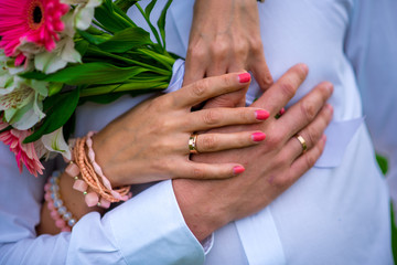 Beautiful and sophisticated wedding bouquet close-up holds the bride in her hands next to the groom. Wedding bouquet, and rings