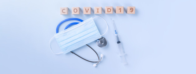 COVID-19 word wooden cube with mask, medical equipment, world disease pandemic infection and prevention concept, top view, flat lay, overhead design