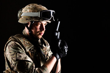 Fototapeta premium Soldier with gun is on mission on black background. Concept of war.