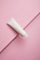Top view of cosmetic cream tube on pink background