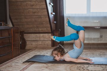 Little cute girl is practicing gymnastics at home. Online training. Quarantine. Stay at home.