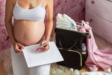 pregnant vwoman with notepad and checklist preparing for baby to be born