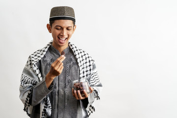 muslim male with a bowl of dates fruit over white background eating for iftar breaking fast