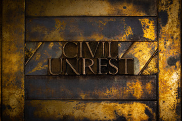 Photo of real authentic typeset letters forming Civil Unrest text on vintage textured grunge copper and gold background
