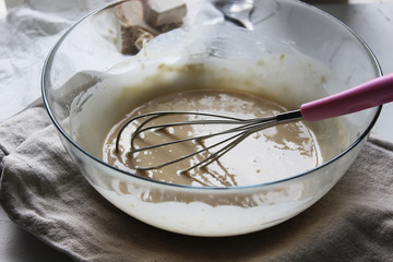 Batter with a whisk in a large glass bowl. Homemade cake. Concept of homework during the quarantine...