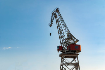 Crane silhoutte in the port with blue sky background. Industrial transportation tower and heavy equipment. Marvel of metal engineering or sea machinery. Sea harbor port. 