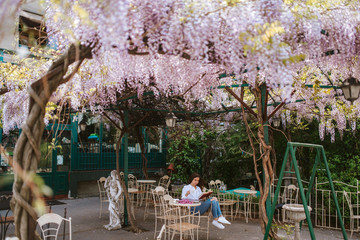 Obraz premium A beautiful young caucasian girl is reading a book in the garden. Spring and flowers