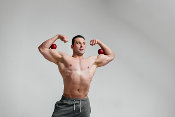 Sporty sexy guy posing on a white background with bright fruits. Diet. Healthy diet