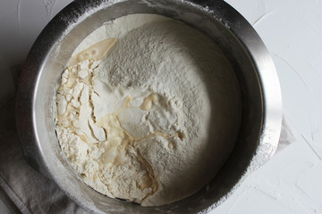 knead the dough in a large metal bowl. Homemade cake. Concept of homework during the quarantine period.