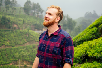Naklejka na ściany i meble redhaired ginger male enjoying morning in India chai plantations Munnar