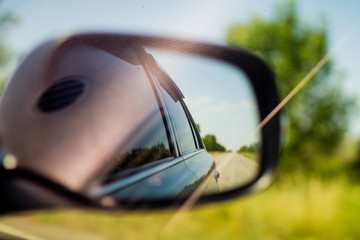 Side mirror of a car, road in a side mirror