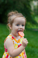 vertical closeup portrait of a cute two year old girl on a background of bright green grass