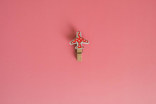 Pink background. Clothespins for photos in the form of an airplane lie on a pink background.