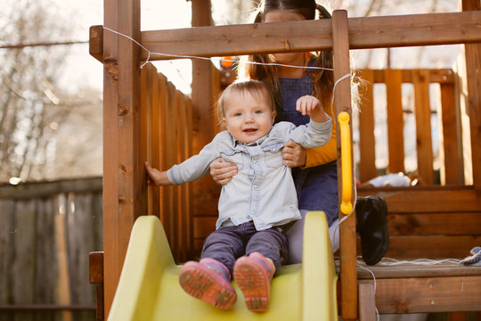 Children ride slide on wooden playground together