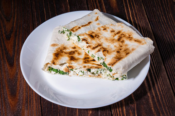 cannelloni, cottage cheese with greens in pita bread on a plate