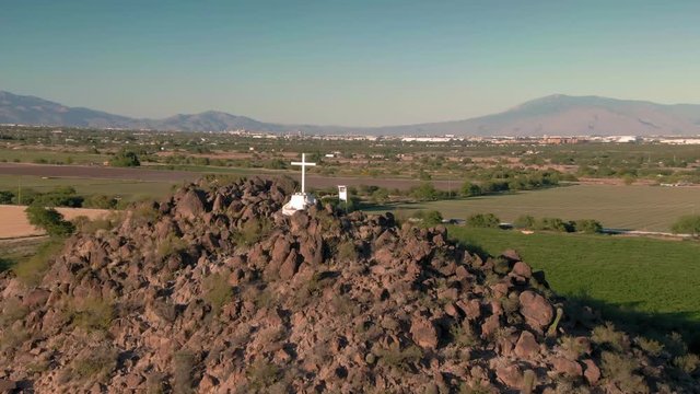 Aerial: Jesus cross on rocky mountain at  Mission San Xavier del Bac. Tucson, Arizona, USA