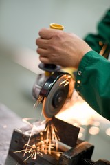 Worker cutting metal hand work angle grinder sparks.