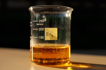 A chemical reaction to produce liquid bromine in a beaker, in the sunlight. - obrazy, fototapety, plakaty
