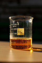 The formation of red liquid bromine in a beaker with a volume of 250 milliliters. - obrazy, fototapety, plakaty