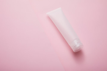 High angle view of plastic cosmetic cream tube on pink background