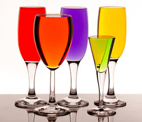 Glasses with multicolored liquid on white background