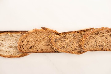 top view of whole grain bread slices in line on white background