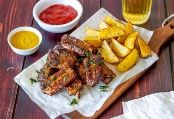 Pork ribs with potatoes on a wooden background. Barbecue. Grill. American cuisine. Recipe.