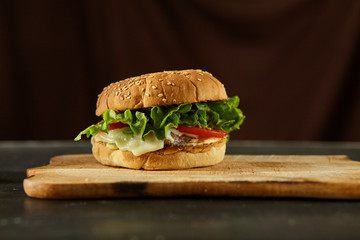 fresh tasty burger isolated on black wooden background with ingredients 