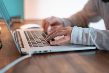 Hands pictured on the keyboard of a laptop typing something. 