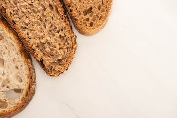 top view of fresh brown bread slices on white background
