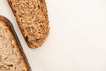 top view of fresh brown bread slices on white background
