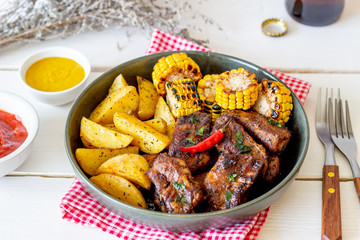Pork ribs with potatoes on a wooden background. Barbecue. Grill. American cuisine. Recipe.