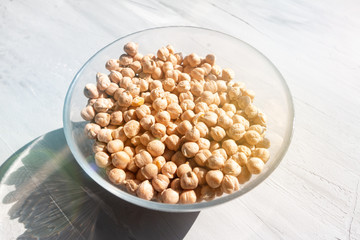 chickpea in a glass bowl on a grey table top view natural sunlight and hard shadow. Healthy dietary food concept
