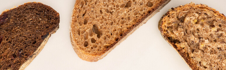 top view of fresh brown bread slices on white background, panoramic shot