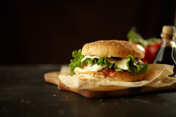 fresh tasty burger isolated on black wooden background with ingredients 