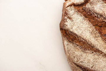top view of fresh brown bread loaf on white background with copy space