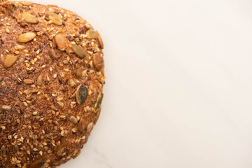 top view of fresh whole wheat bread loaf with seeds on white background with copy space
