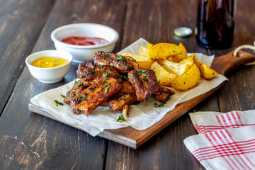 Pork ribs with potatoes on a wooden background. Barbecue. Grill. American cuisine. Recipe.