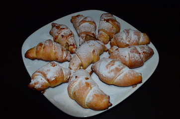 Homemade pastry. Bagel, Croissants in a white plate on a dark background.