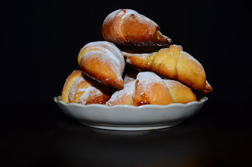 Homemade pastry. Bagel, Croissants in a white plate on a dark background.