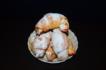 Homemade pastry. Bagel, Croissants in a white plate on a dark background.