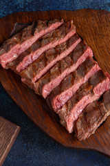 Ready striploin steak on a wooden panel.