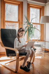 Beautiful 9 year old brunette girl playing with a tablet computer and smiling, studying at home