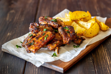 Pork ribs with potatoes on a wooden background. Barbecue. Grill. American cuisine. Recipe.