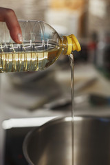 Close up of pouring vegetable oil into deep stainless steel pot